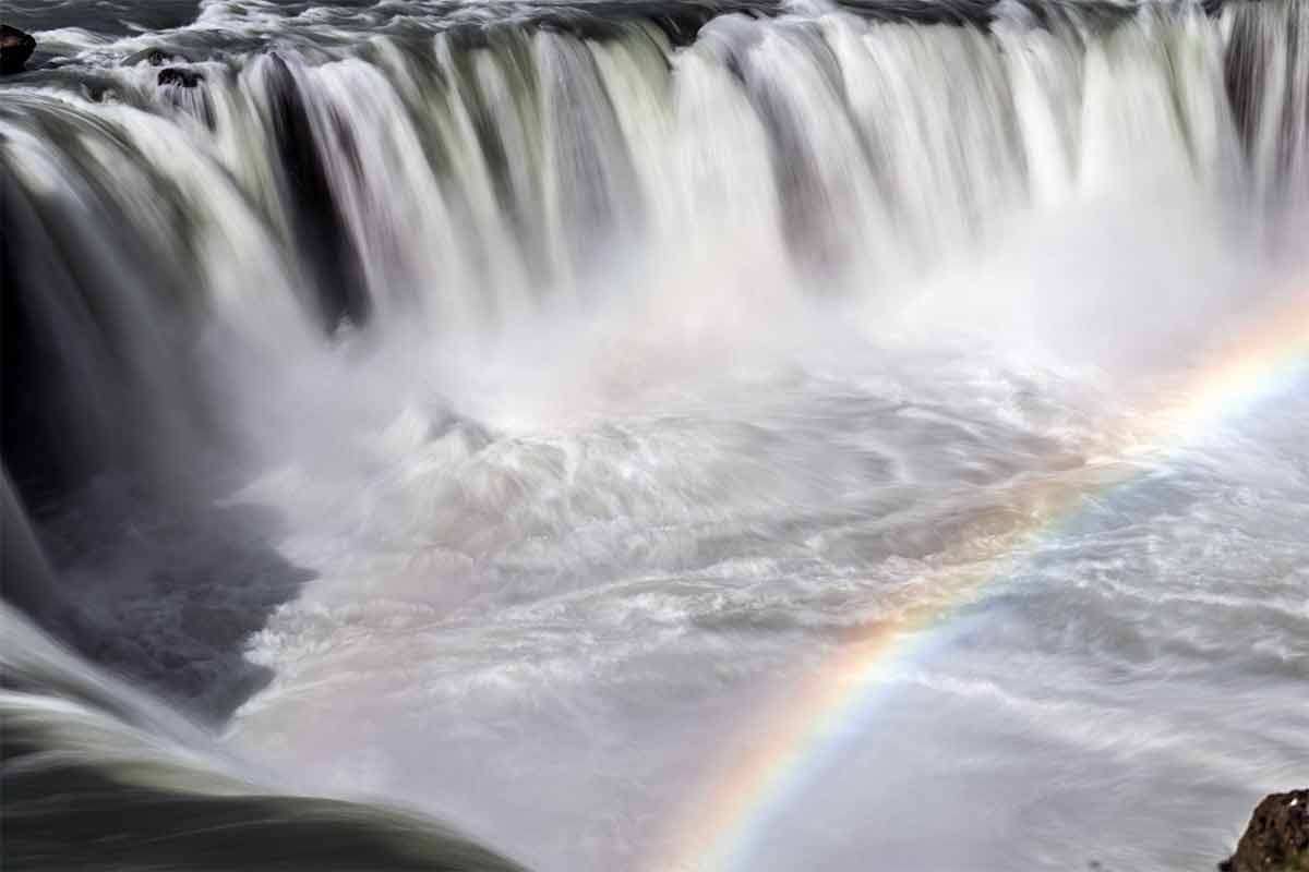 Goðafoss (Ostseite). Das tosende Wasser erzeugt bei Sonnenschein einen wunderschönen
                        Regenbogen